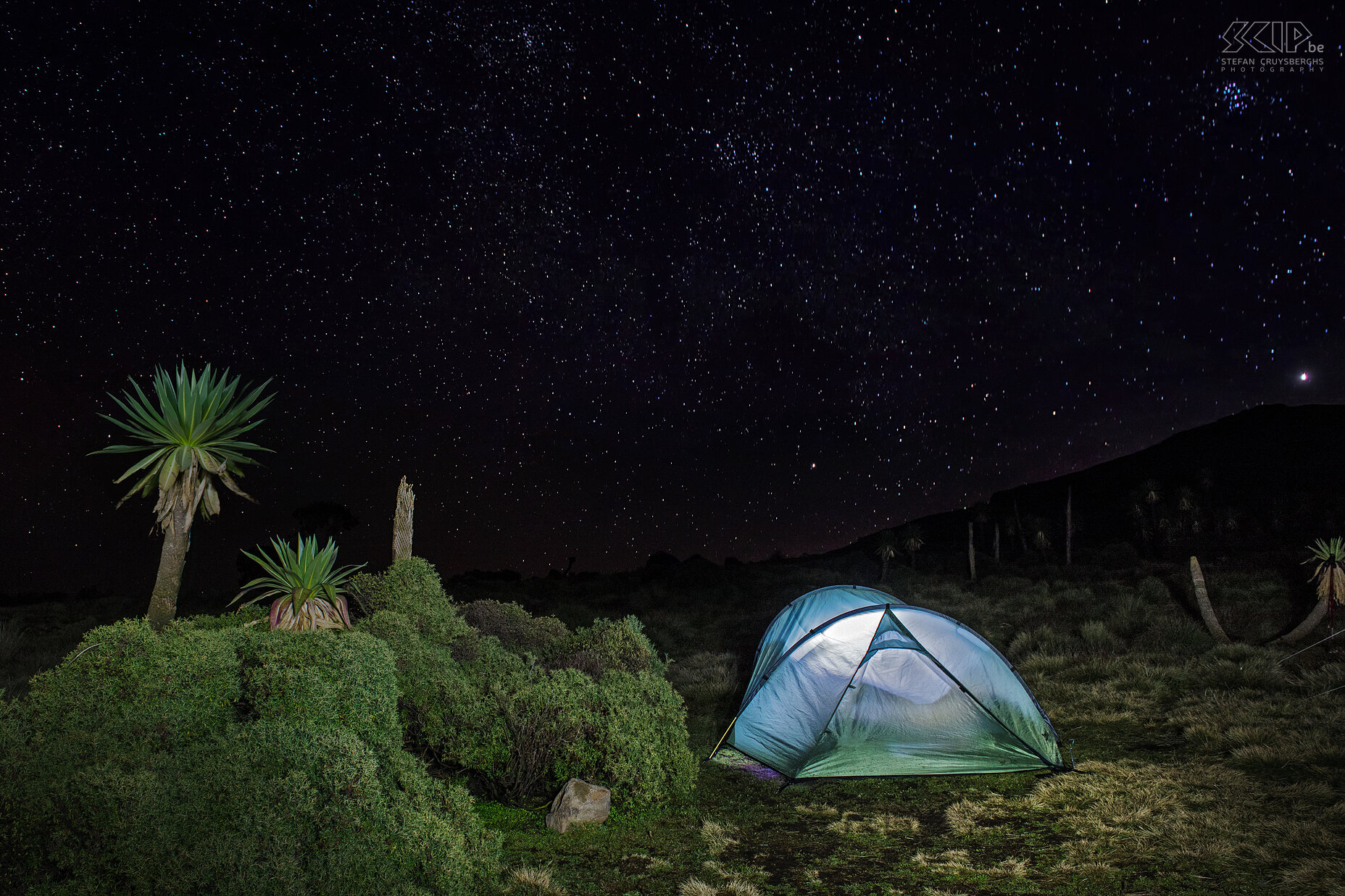 Simien Mountains - Ghenek - Tent met sterrenhemel Tijdens onze laatste nacht in de Simien Mountains was er een prachtige sterrenhemel. Ik had graag een uur lang sterrensporen gefotografeerd, maar het was er ontzettend koud, dus is het bij een paar nachtopnames gebleven. De voorgrond heb ik belicht met mijn zaklamp. De heldere poolster staat rechtsboven de heuvel. Stefan Cruysberghs